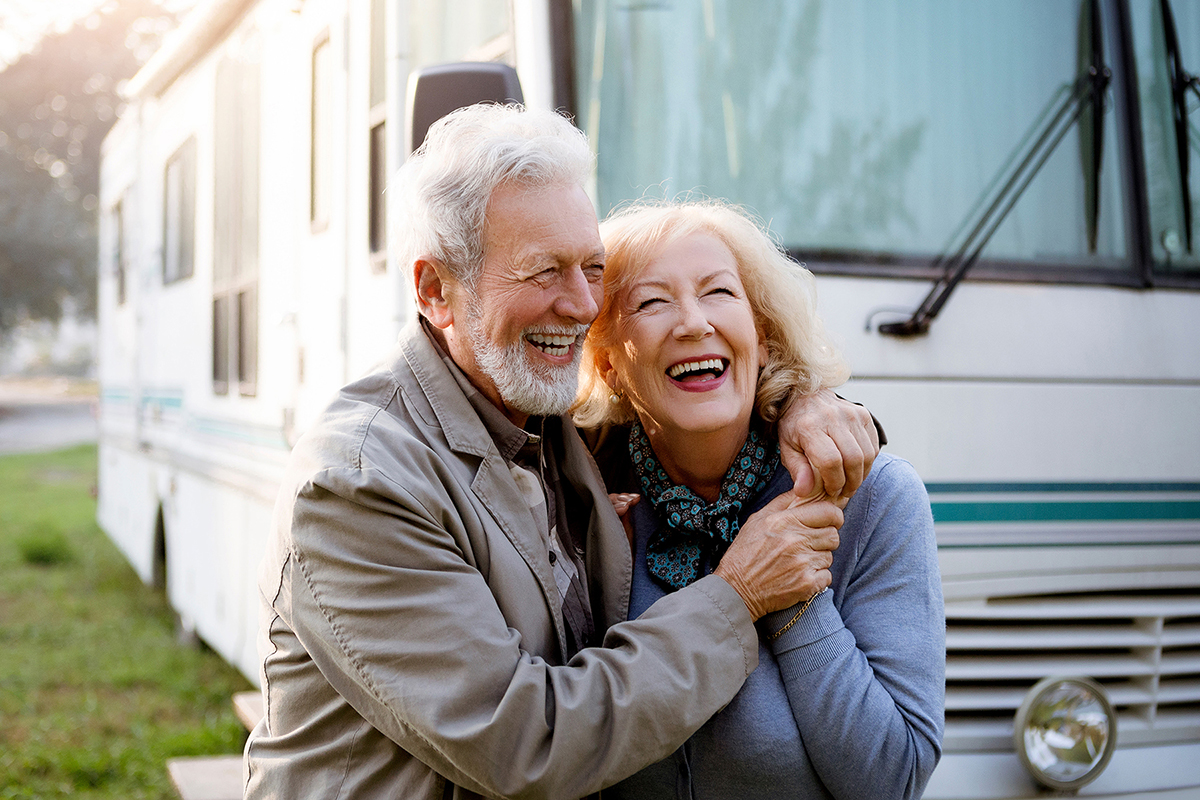 Picture of older couple smiling and laughing in front of motorhome