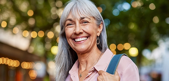 Older adult standing outdoors holding a bag