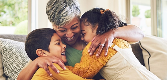 Older adult hugging two children on a couch