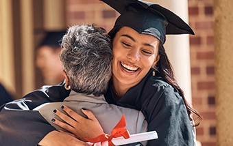 Graduate hugging an older adult on graduation day