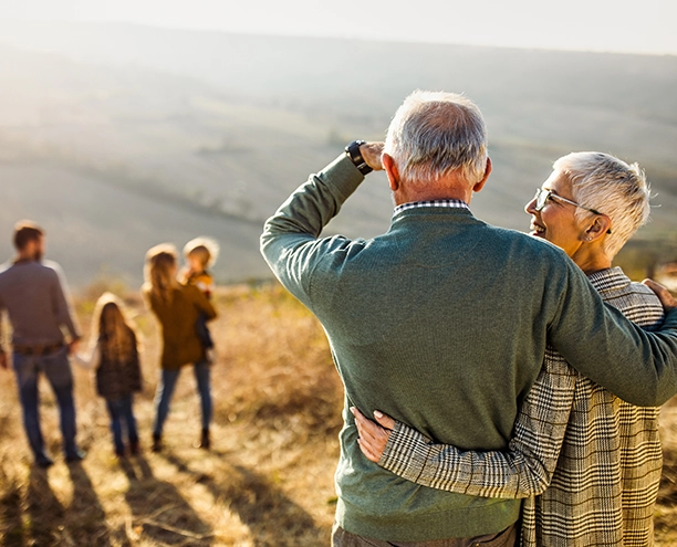Older adults standing together looking at family outdoors