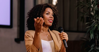 A speaker holding a microphone speaking to an audience