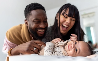 Parents holding a baby together indoors