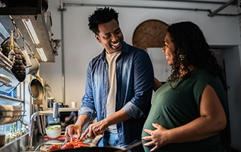 Pregnant woman cooking meal with partner