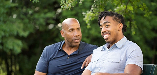 Father and adult son sitting on a park bench